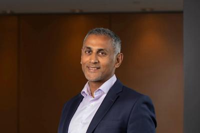 Man in glasses, smiling, headshot, professional, light background.