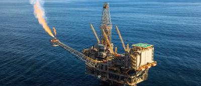 Offshore gas platform with flames, ocean, and sky.