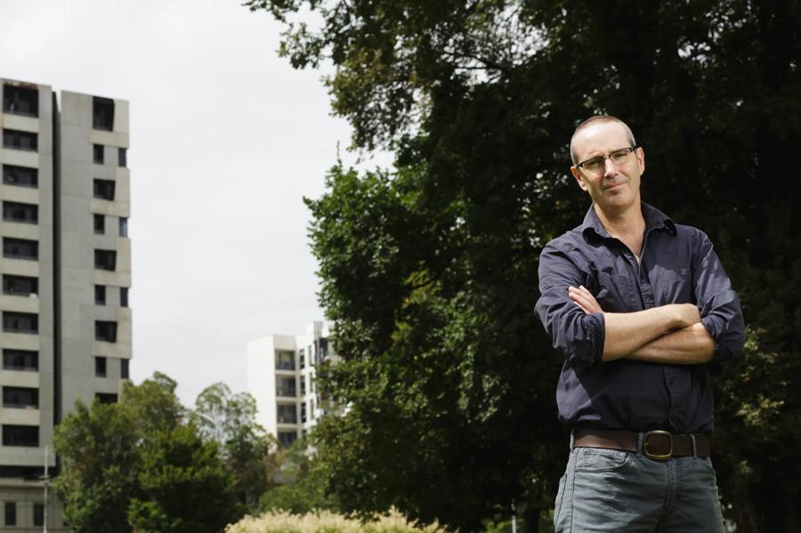Paul Sinclair, ACF Director of Campaigns, arms folded in a park with apartment towers behind him