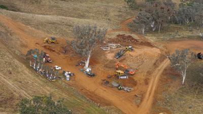 Land cleared for agriculture, showing brown earth, trees, and sky.