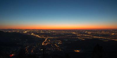 Sunset over city skyline, silhouetted buildings, orange and purple sky.