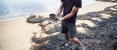 Dan Ash, a man, smiling, wearing a blue shirt, standing outdoors, trees in background.