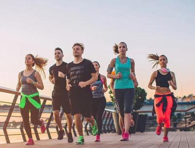 People running a fun run, banner overhead, sunny day.