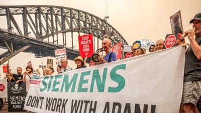 Siemens and Adani logos side-by-side, with a blue background.