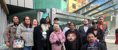 Rawlinson Award winner, smiling, holding trophy, with background of people and stage.