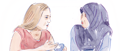 Two people chatting, one with a laptop, in a bright room.