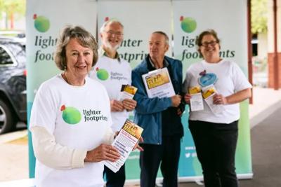 Woman smiling, holding microphone, speaking at event, outdoor setting.