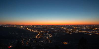 Sunset over a city skyline with silhouetted buildings and vibrant orange and purple sky.
