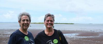 A person in a forest, standing near a large tree, sunlight filtering through the canopy.
