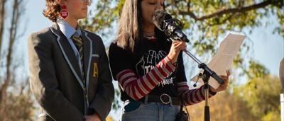 Woman speaking at a podium, microphone present. Backdrop with logo.