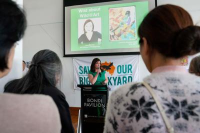 Wild At Art Bondi Exhibition sign, colorful art, beach background.