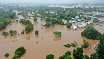 Lismore floods 2022: Aerial view of flooded town, houses submerged, brown water.