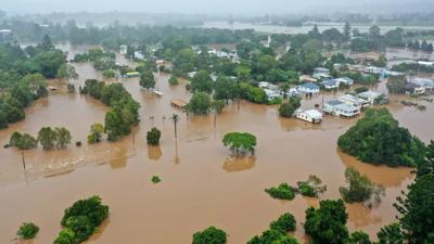 Lismore floods 2022: Aerial view of flooded town, houses submerged, brown water.