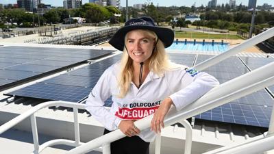 Solar panels on Gold Coast building rooftop, blue sky.