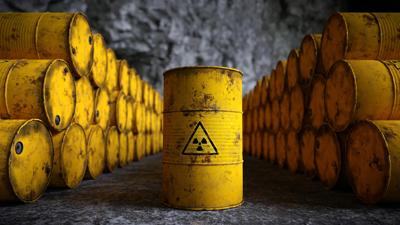 Barrels of radioactive waste, stacked, outdoors.