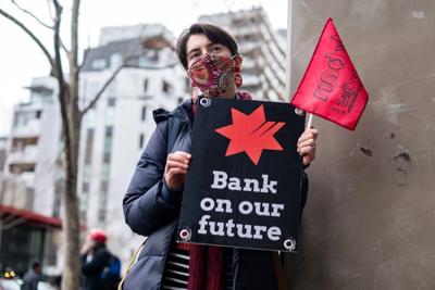 Man in field, holding camera, blurred background, sunny day.