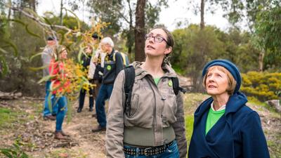 Large group of people, outdoor event, banner, stage, sunny day.