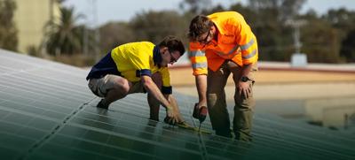 Solar panels on a roof, installers working.