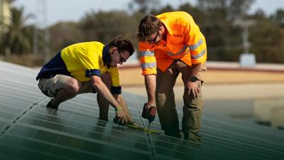Solar panels on a roof, installers working.