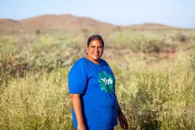 Two people smiling, standing outdoors. One holds a camera. Karratha, WA.