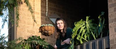 Woman smiling, wearing hat, outdoors, trees in background.