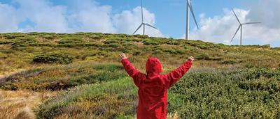 Repowered wind turbine, blue sky, green landscape, power lines.