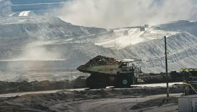 Coal truck on road, dust cloud, industrial landscape, blue sky.