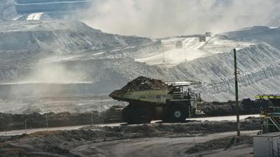 Coal truck on road, dust cloud, industrial landscape, blue sky.