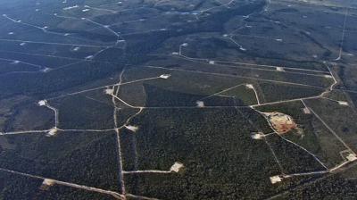Gas field infrastructure with pipelines and storage tanks under a blue sky.