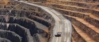 Woman in a white coat, smiling, holding a plant in a lab setting.