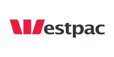 A person in a blue shirt is holding a phone, standing in front of a Westpac building.