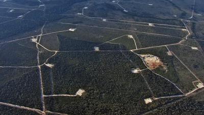 Gas field infrastructure with pipelines and storage tanks under a blue sky.