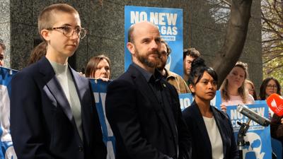 Man speaking at a podium, ACF logo, crowd in background, outdoor setting.