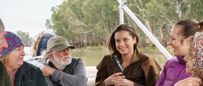 Group of people, some wearing vests, posing outdoors after training.