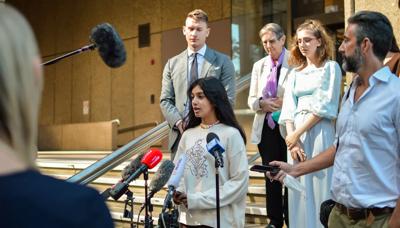 Woman in court, holding papers, facing camera.