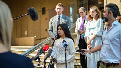 Woman in court, holding papers, facing camera.
