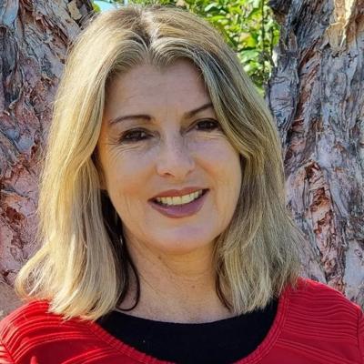 Woman smiling, headshot, outdoors, natural light.