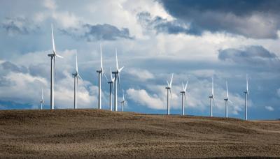 Wind turbines in a field, blue sky background.