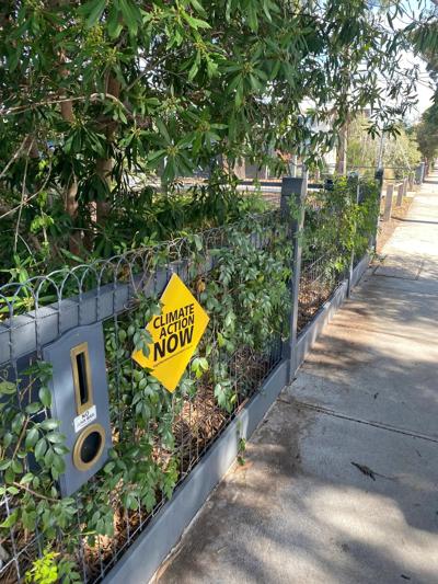Sign on fence: "Climate Now" and "Together We Can" messaging, election context.
