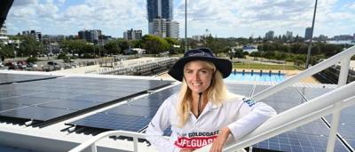 Woman smiling, holding a baby, outdoors.