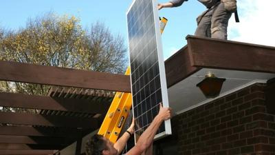 Solar panel installation on a rooftop, showing panels, roof structure, and sunlight.