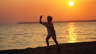 Boy flying a kite in sunlight.