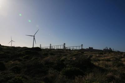 Hilly landscape with wind turbines under a cloudy sky.