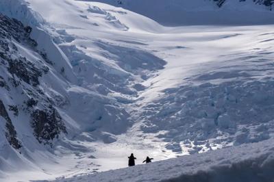 Snowy Antarctic landscape with mountains, ice, and a blue sky.