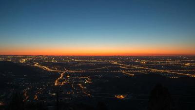 Sunset over a city skyline, silhouetted buildings, orange and purple sky.
