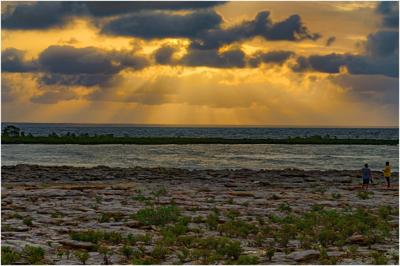 Sunset over Darwin Harbour, Australia. Orange sky, calm water, silhouette of land.