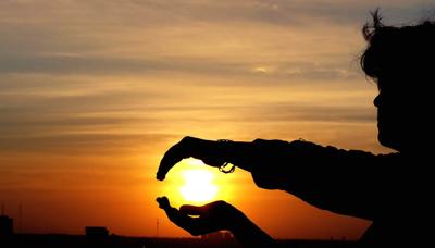 Sun shining on hands, reaching up.