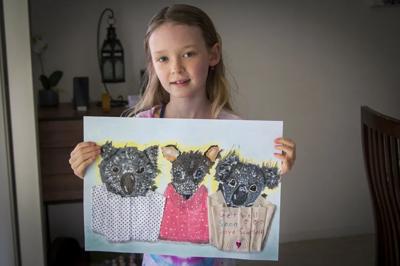 Woman with red hair, holding a paintbrush, painting on a canvas outdoors.