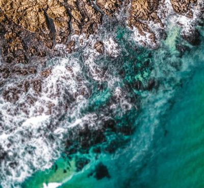 Ocean waves crashing on a sandy beach, blue water, white foam.