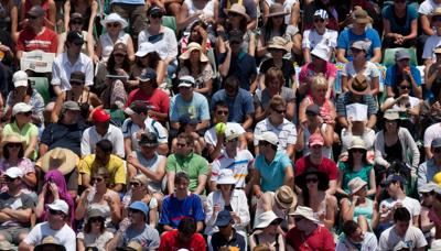 Tennis crowd watching a match, players unseen. Bright sunny day.